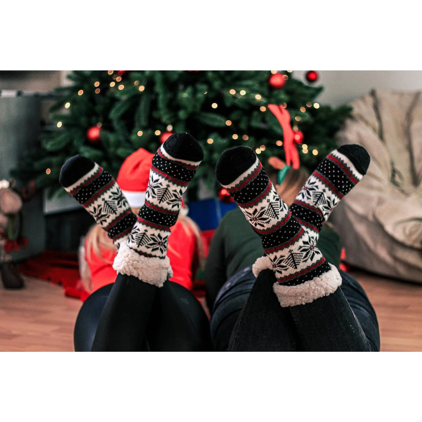 Wintersocken von MYSOX, gemütlich vor einem Weihnachtsbaum an zwei Mädchen